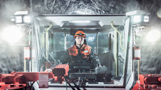 A man driving a vehicle in an underground mine.