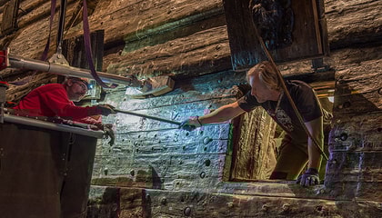 Two persons exchanging a bolt at the Vasa ship.