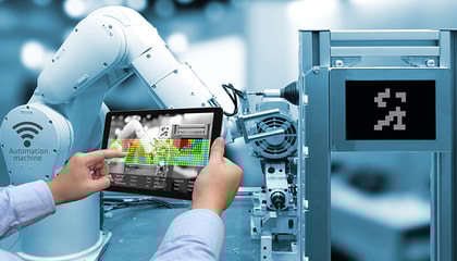 Hands holding a tablet in front of an industrial robot.