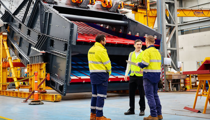 Three men talking to each other standing in an industrial environment