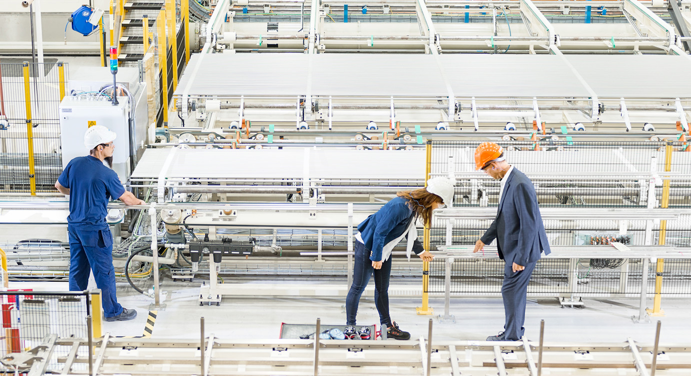 Three persons in factory.