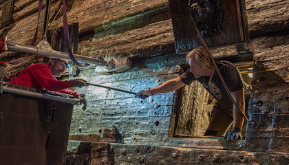 Two persons exchanging a bolt at the Vasa ship.