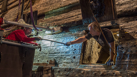 Two persons exchanging a bolt at the Vasa ship.