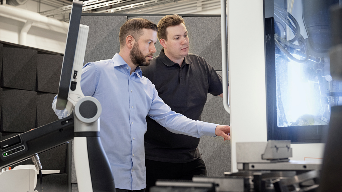 Two men in from of a CNC machine.