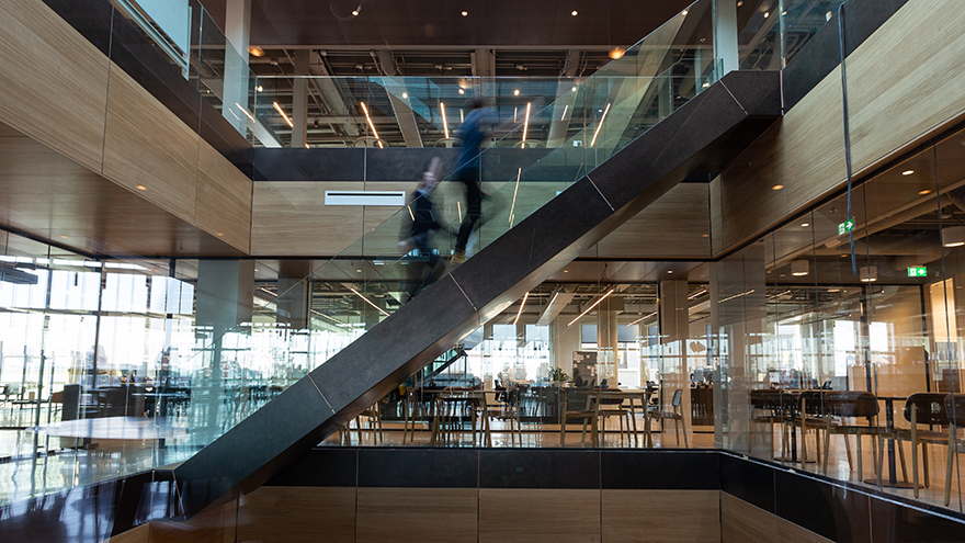 Two persons who are blurry because they are moving up a stair in a modern office environment