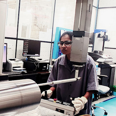 A woman in work clothes and gloves operating an industrial machine.