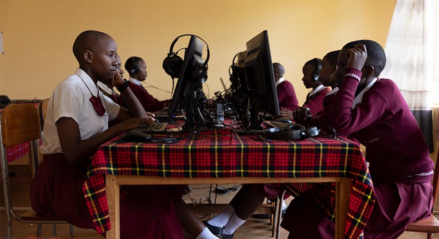 Six young girls sitting around a table and look at computers in a school builing in Mavuno, Tanzania